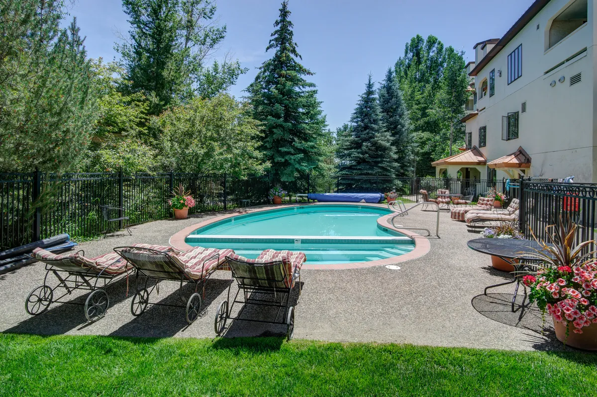 A tranquil outdoor pool area surrounded by lush greenery and lounge chairs. The inviting scene suggests relaxation and leisure after a day of mountain activities, highlighting the resort-style amenities available to guests.